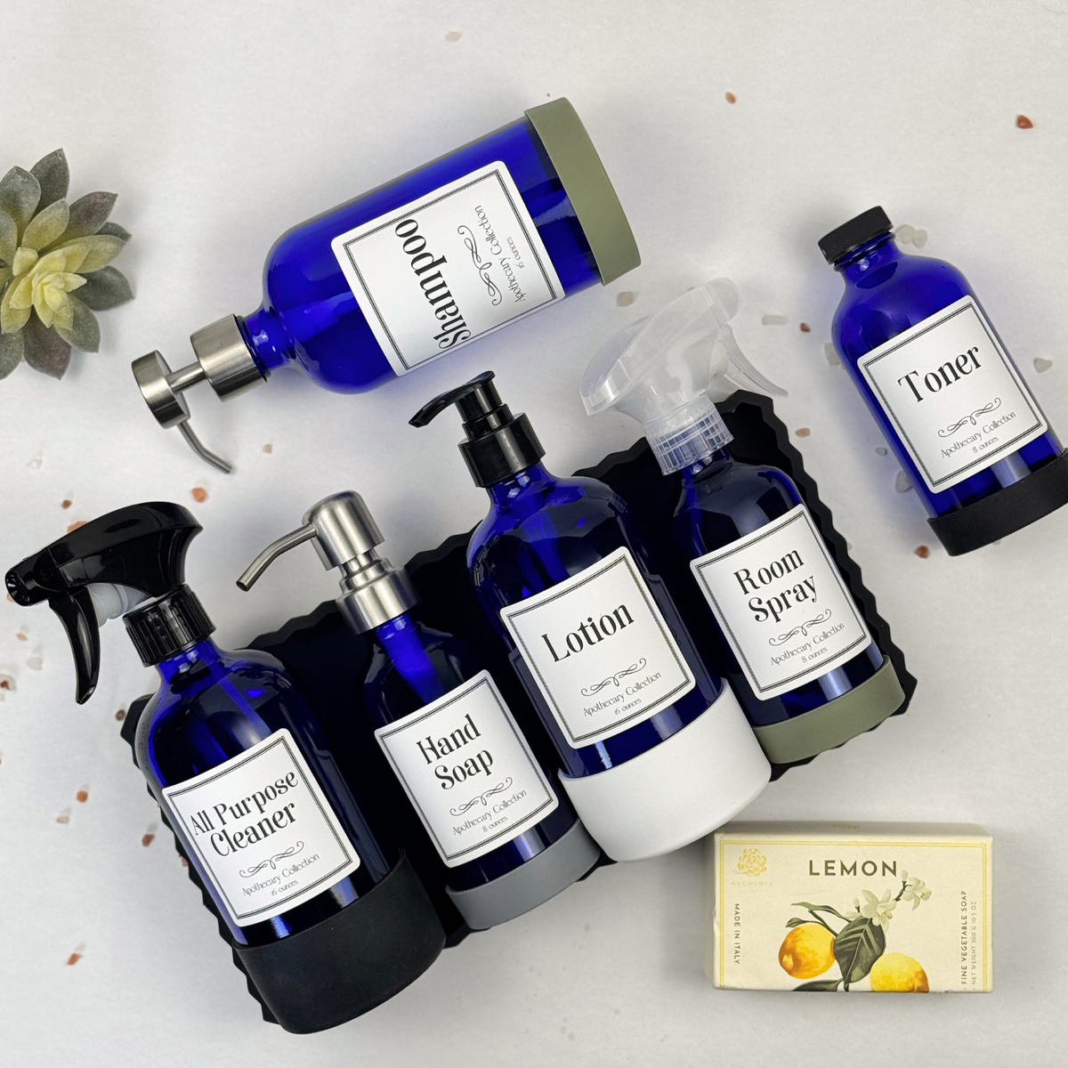 Cobalt blue glass dispenser with silicone sleeve shown with available pump, sprayer and cap tops and Apothecary label