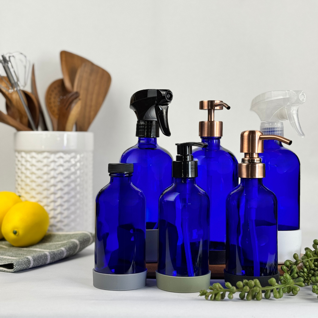 Cobalt blue glass dispenser with silicone sleeve shown with multiple pump and spray top styles