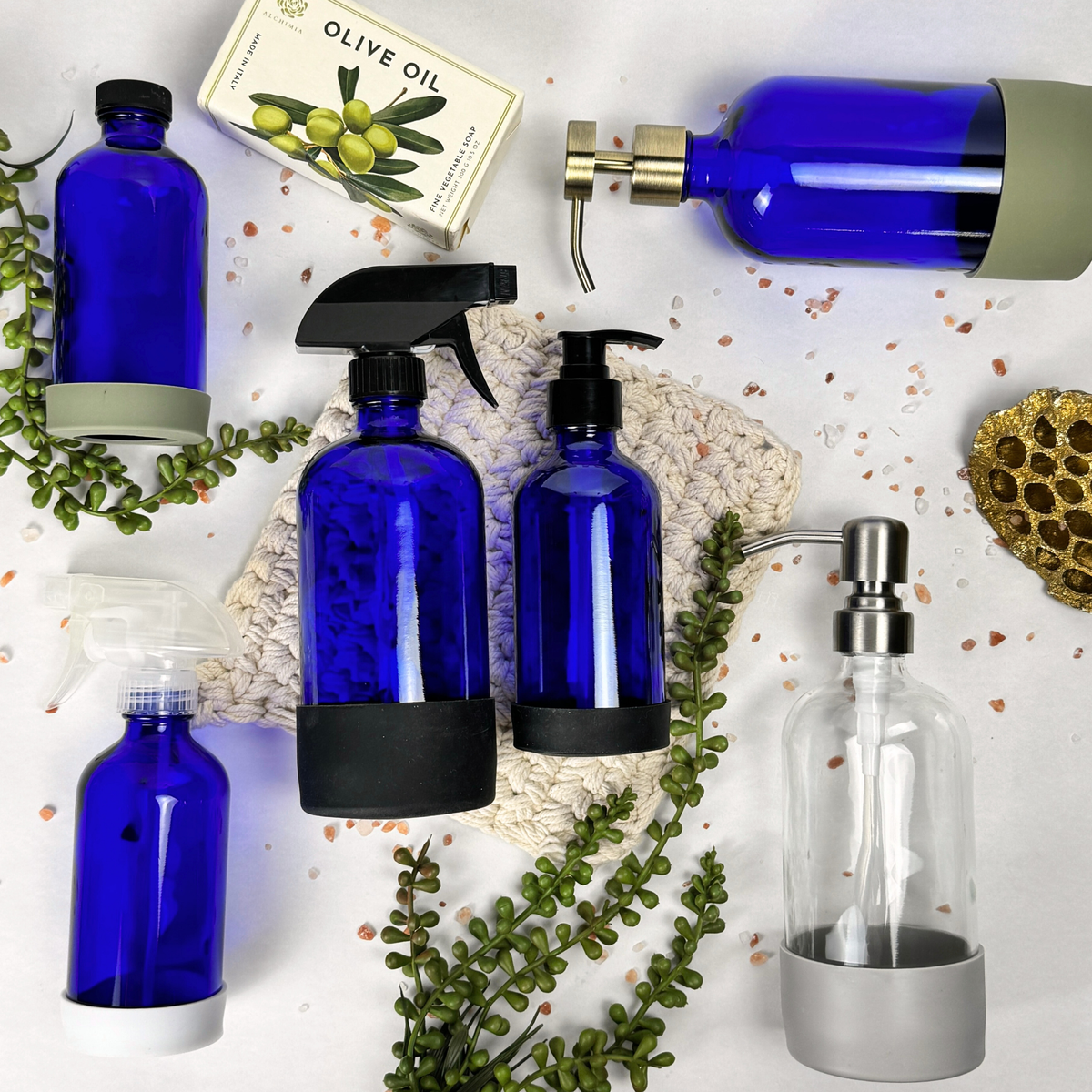 Cobalt blue glass dispenser with silicone sleeve shown with available pump, sprayer and cap tops