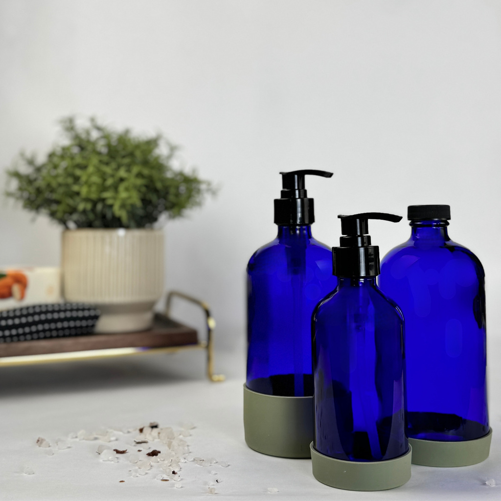 Cobalt blue glass dispenser with silicone sleeve showing plastic pump and cap options