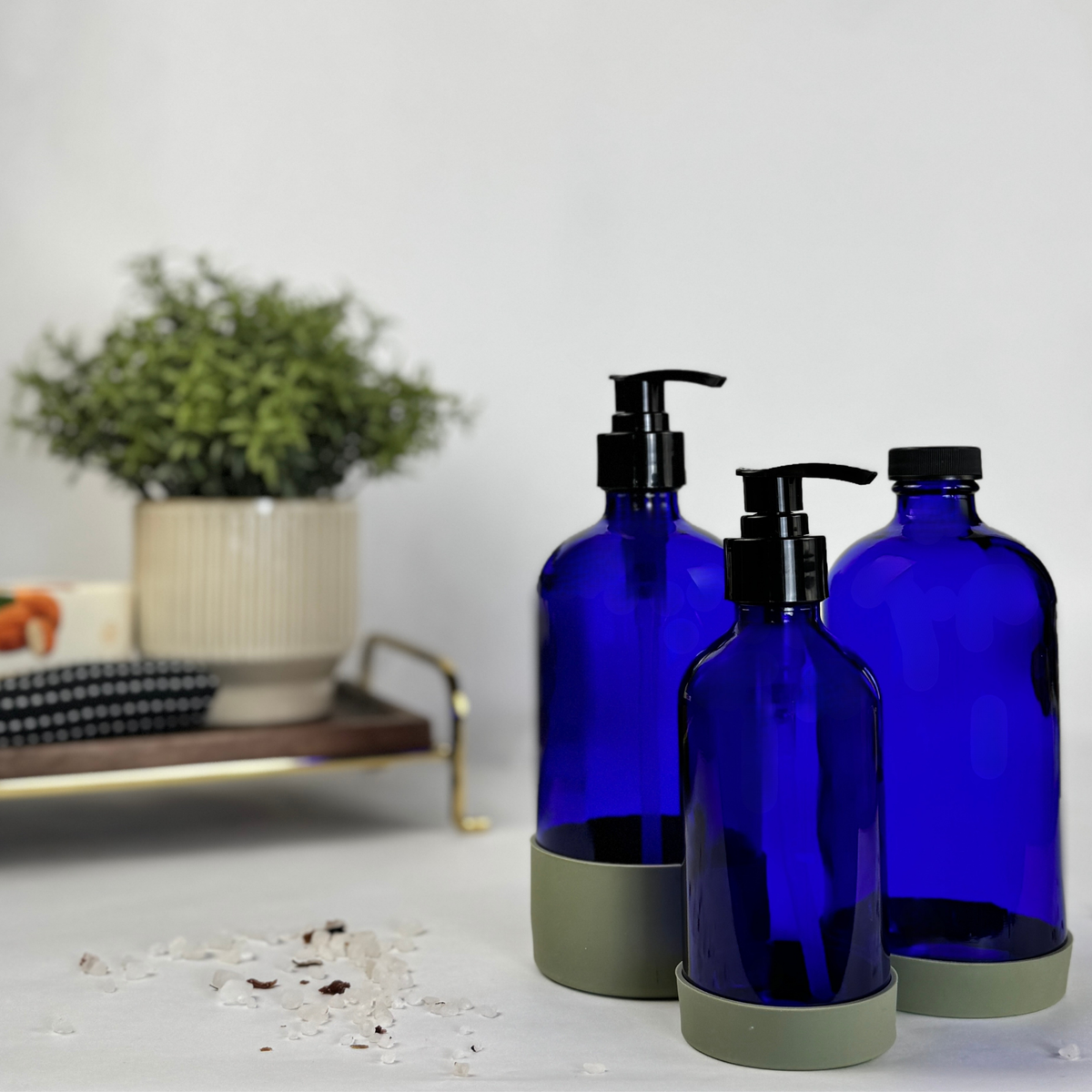 Cobalt blue glass dispenser with silicone sleeve showing plastic pump and cap options