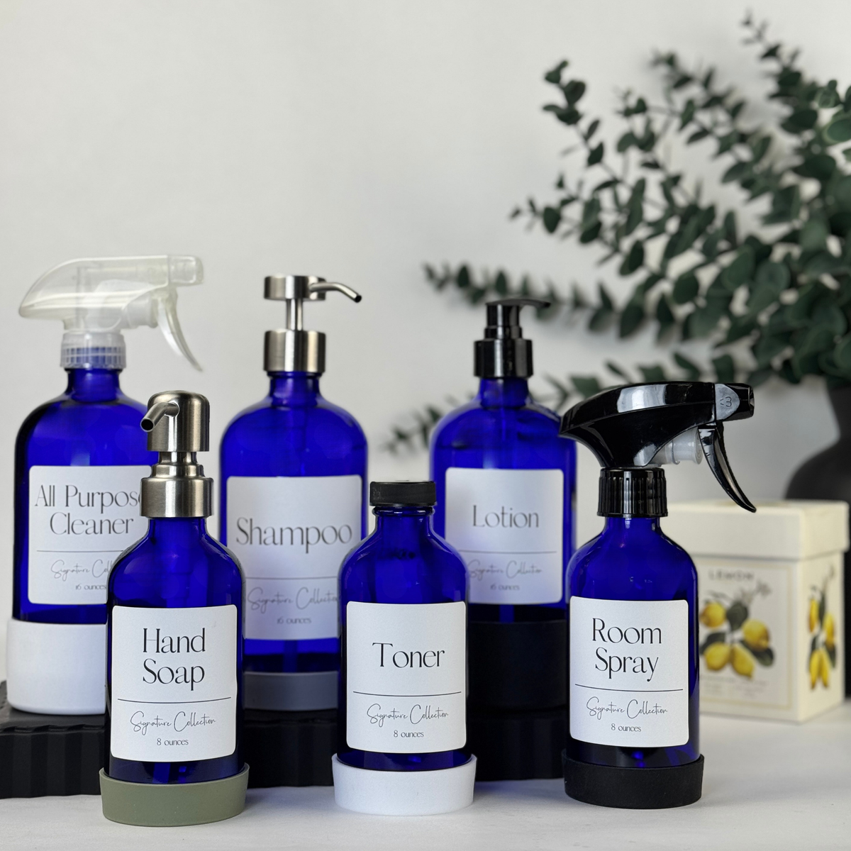 Cobalt blue glass dispenser with silicone sleeve shown with multiple pump and spray top styles